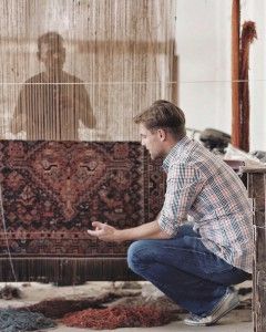 Alex in India looking at a handmade rug
