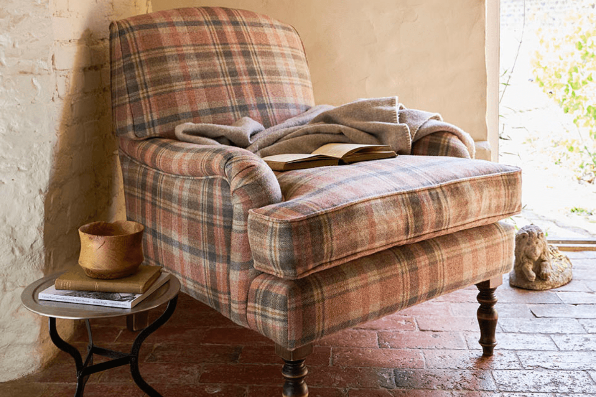 Chair in autumn checked red, grey and yellow fabric with a blanket and books on the seat